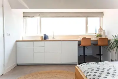 a kitchen with white cabinets and a desk in a room at Bamboa Beachhouse in Zandvoort