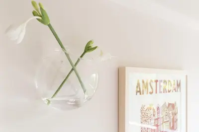 a vase with a flower in it next to a book at Empire suites garden view in Amsterdam