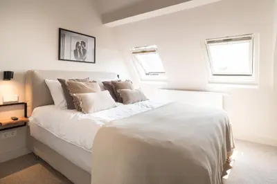 a white bedroom with a large white bed with pillows at Empire suites garden view in Amsterdam