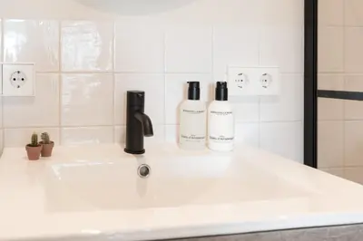 two bottles of wine sitting on a bathroom sink at Empire suites garden view in Amsterdam