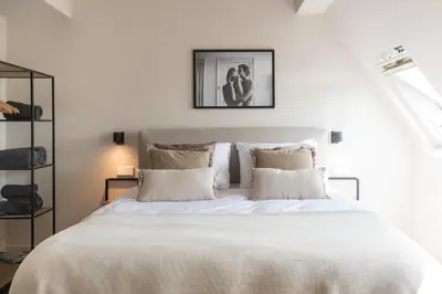 a bedroom with a large bed with white sheets and pillows at Empire suites garden view in Amsterdam