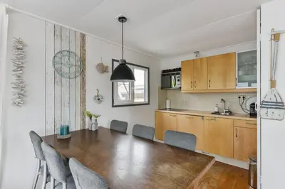 a kitchen and dining room with a wooden table and chairs at Bright and Comfortable Houseboat in Aalsmeer