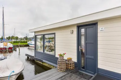 a house on a dock with a boat in the water at Bright and Comfortable Houseboat in Aalsmeer