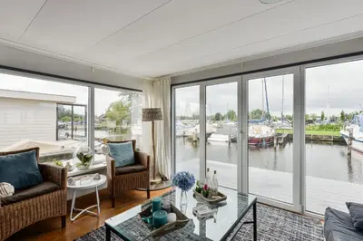 a living room with a view of a marina at Bright and Comfortable Houseboat in Aalsmeer