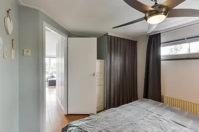a bedroom with a ceiling fan and a bed at Bright and Comfortable Houseboat in Aalsmeer