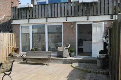 a patio with a wooden bench and a building at Studio Sautille in Zandvoort
