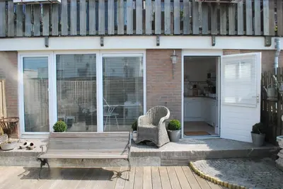 a patio with a wooden table and a bench at Studio Sautille in Zandvoort