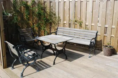 a wooden bench and a picnic table on a deck at Studio Sautille in Zandvoort