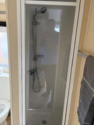 a man standing in a shower in a bathroom at Chalet De Duinberg in IJmuiden
