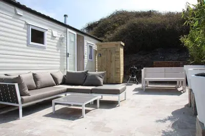 a patio with a couch and a table and a bench at Chalet De Duinberg in IJmuiden