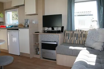 a living room with a couch and a flat screen tv at Chalet De Duinberg in IJmuiden