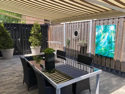 a patio with a table and chairs and a fence at Design BB Bed&Bike holiday cottage Tiny Home in Spakenburg in Spakenburg