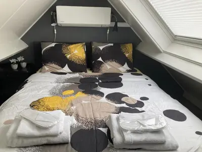 a bed with a comforter and pillows on it at Design BB Bed&Bike holiday cottage Tiny Home in Spakenburg in Spakenburg