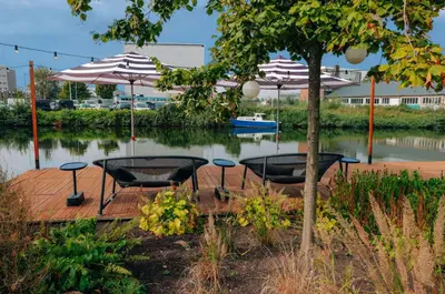 two tables and chairs with umbrellas on a wooden deck at YOTEL Amsterdam in Amsterdam