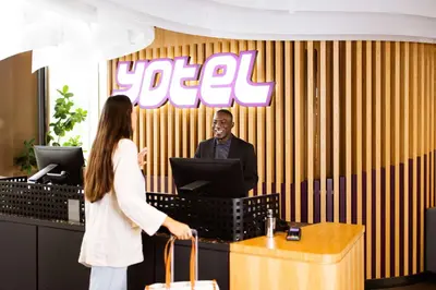a man and a woman standing at a desk with a computer at YOTEL Amsterdam in Amsterdam