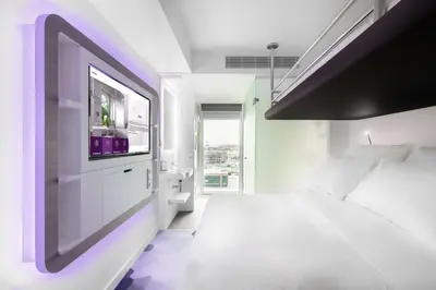 a bedroom with a white bed and a tv on the wall at YOTEL Amsterdam in Amsterdam