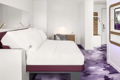 a white bed in a room with purple floors at YOTEL Amsterdam in Amsterdam