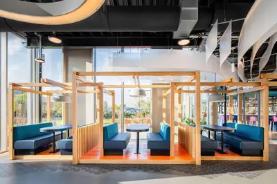 a waiting area with blue chairs and tables and windows at YOTEL Amsterdam in Amsterdam
