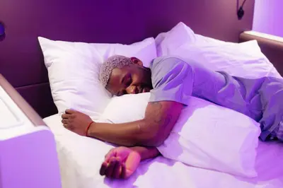 a man sleeping in a bed with his head on a pillow at YOTEL Amsterdam in Amsterdam