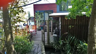 a wooden walkway leading to a house with a porch at Houseboat Vliegenbos in Amsterdam