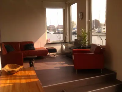 a living room with red furniture and a large window at Houseboat Vliegenbos in Amsterdam