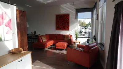 a living room with a red couch and orange chairs at Houseboat Vliegenbos in Amsterdam