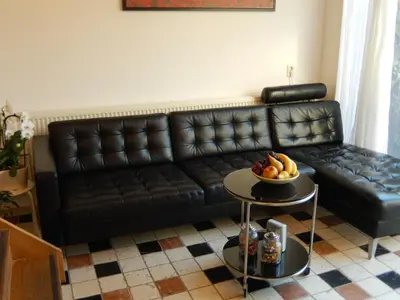 a black leather couch in a living room with a bowl of fruit at Apartment Amsterdam New West - Free parking in Amsterdam