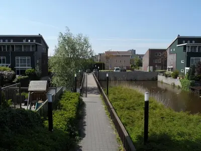 a walkway with a bench next to a river at Apartment Amsterdam New West - Free parking in Amsterdam