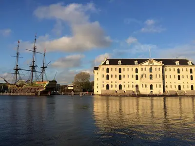 a large white building with a tall ship in the water at Amsterdam House of Arts & Crafts in Amsterdam
