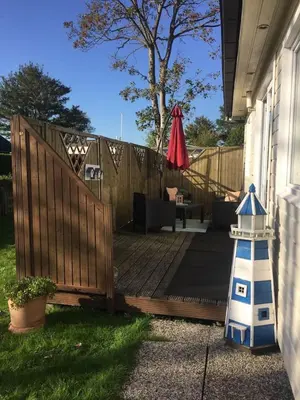 a wooden deck with a lighthouse next to a house at Haus zum Leuchtturm Ferienpark Vislust Niederlande Ijsselmeer in Wervershoof