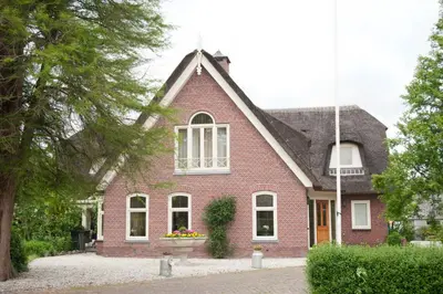 a red brick house with a window at Apartement De Vosseburch in Langeraar