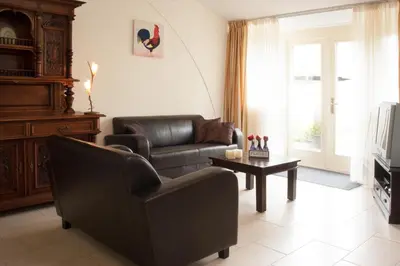 a living room with a couch and a chair and a table at Apartement De Vosseburch in Langeraar