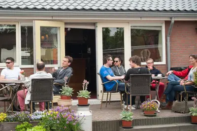 a group of people sitting at tables on a patio at Apartement De Vosseburch in Langeraar