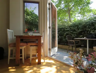 a table and chairs in a room with a window at Casa duna Oceans terrace and Ocean spray garden close to the beach and city centre in Zandvoort