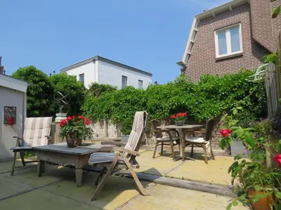 a patio with a wooden table and chairs and a table at Casa duna Oceans terrace and Ocean spray garden close to the beach and city centre in Zandvoort