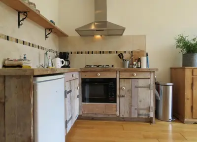a kitchen with wooden cabinets and a stove top oven at Casa duna Oceans terrace and Ocean spray garden close to the beach and city centre in Zandvoort