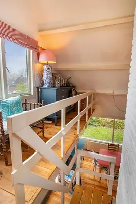 a room with a white rail and a table and chairs at Het Zeepaartje, knus en gezellig in Noordwijkerhout