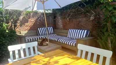 a patio with two chairs and a table with an umbrella at Het Zeepaartje, knus en gezellig in Noordwijkerhout