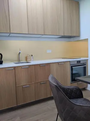 a kitchen with wooden cabinets and a sink and a chair at Beachtime Suite in Zandvoort