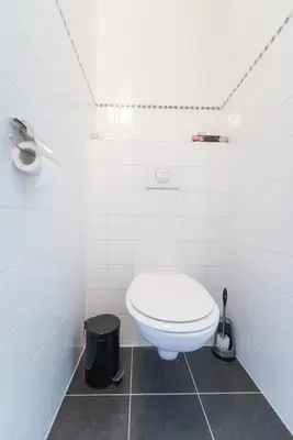 a white bathroom with a toilet and a trash can at Bed and Breakfast Hoorn in Hoorn