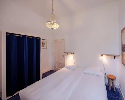 a bedroom with a large bed and a chandelier at Boutique Appartement-Hotel Villa Juttershof in Bergen