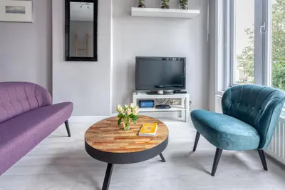a living room with a table and two chairs and a tv at Bed and Breakfast The Rose in Haarlem