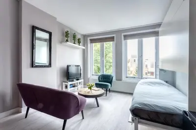 a bedroom with a bed and a chair and a tv at Bed and Breakfast The Rose in Haarlem