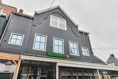a gray building with a green sign on it at Hotel aan de Haven in Volendam
