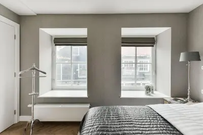 a bedroom with two windows and a bed at Hotel aan de Haven in Volendam