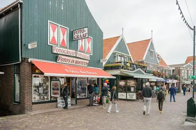 a group of people walking in front of shops on a street at Hotel aan de Haven in Volendam