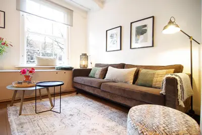a living room with a brown couch and a table at Sonnenberg Canal View in Amsterdam