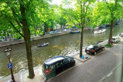 two cars parked next to a river with boats in it at Sonnenberg Canal View in Amsterdam
