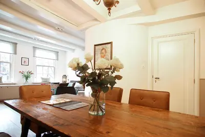 a dining room table with a vase of flowers on it at Sonnenberg Canal View in Amsterdam