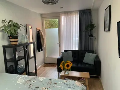 a living room with a black couch and a window at Sunny Place in Zandvoort